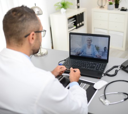 handsome doctor giving a remote medical consultation with senior woman patient over internet computer telemedecine diagnostic