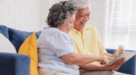 Asian senior couple use tablet video conference with doctor about pill  while sitting on sofa at home,senior learn to use technology.aging at home