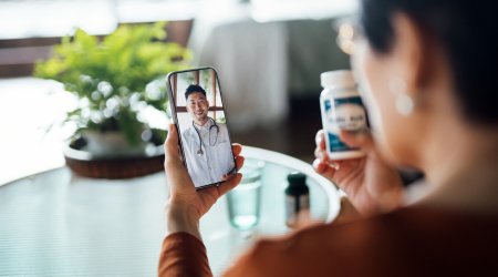 Senior Asian woman having a virtual appointment with doctor online, consulting her prescription and choice of medication on smartphone at home. Telemedicine, elderly and healthcare concept